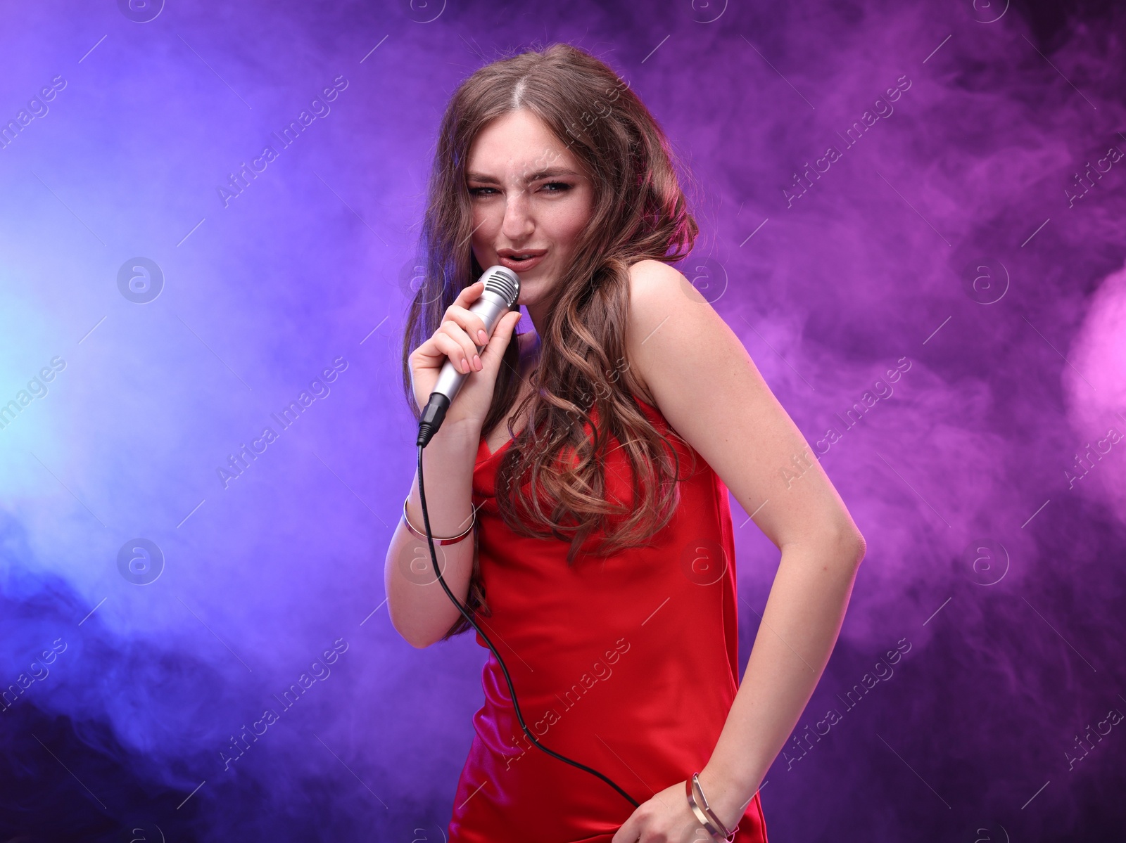 Photo of Beautiful woman with microphone singing in color lights