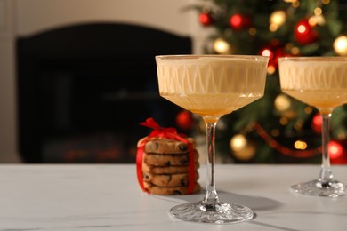 Photo of Tasty eggnog and cookies on white marble table indoors. Space for text