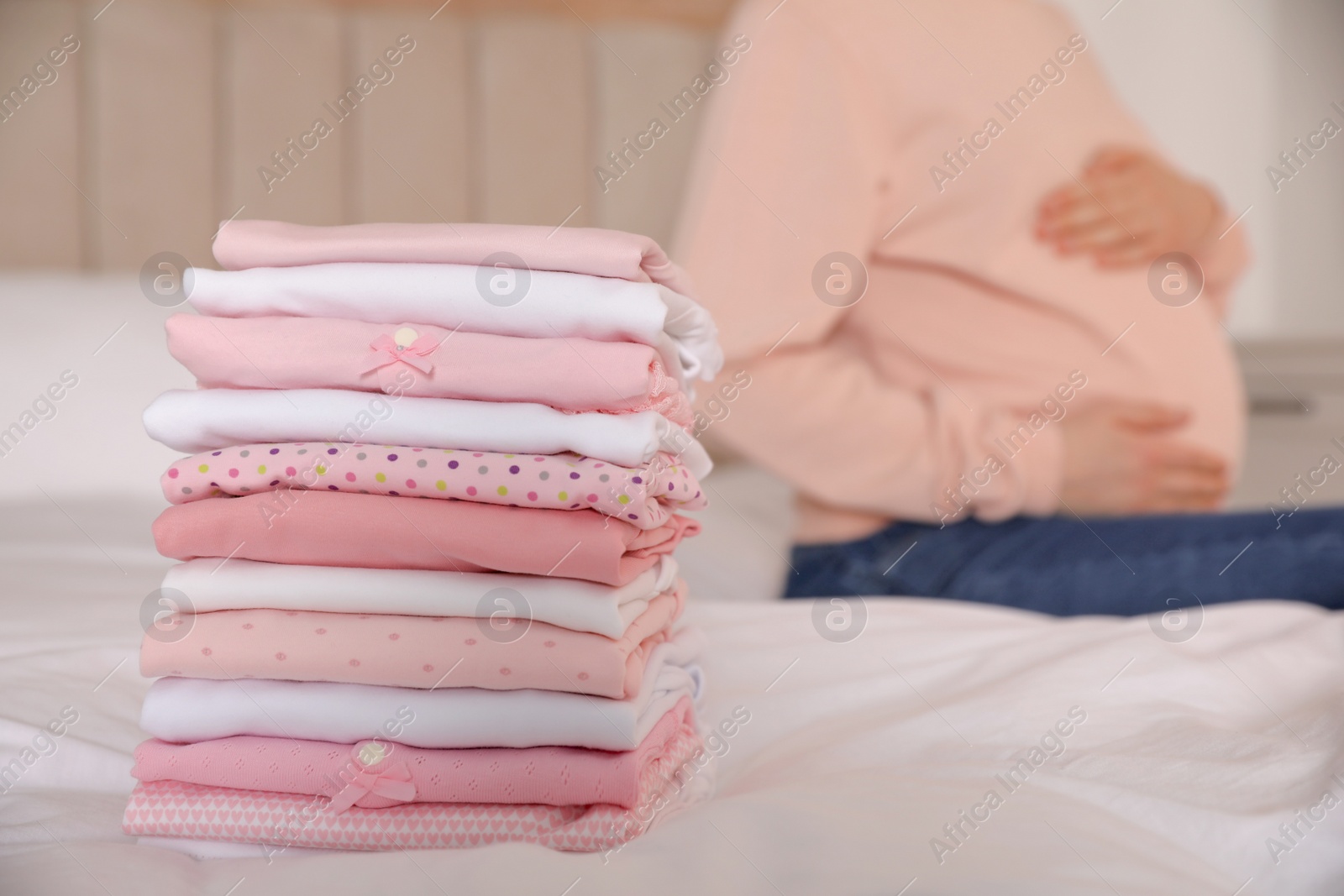 Photo of Pregnant woman in bedroom, focus on girl's clothes