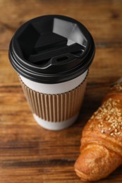 Photo of Coffee to go. Paper cup with tasty drink and croissant on wooden table