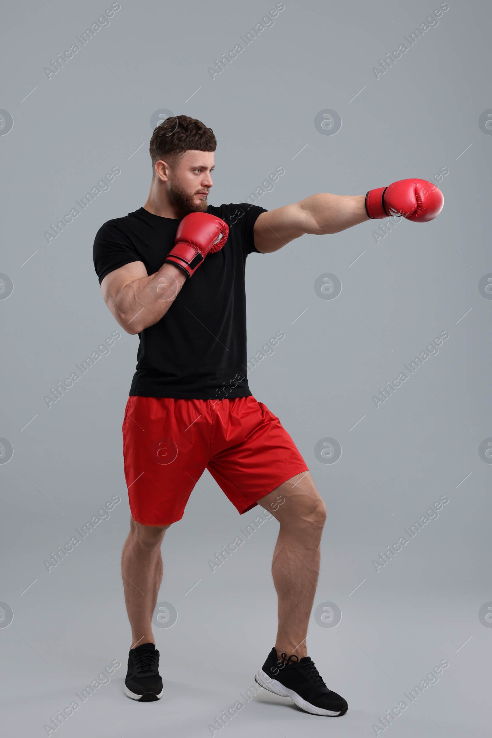 Photo of Man in boxing gloves fighting on grey background