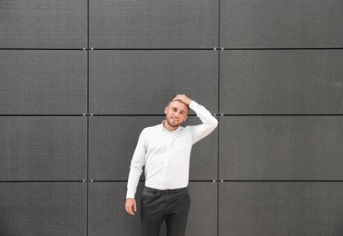 Portrait of handsome young man leaning to wall outdoors