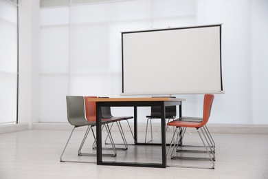 Conference room interior with wooden table and video projection screen