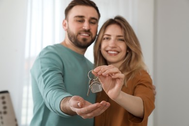Happy young couple with key in new house, focus on hands