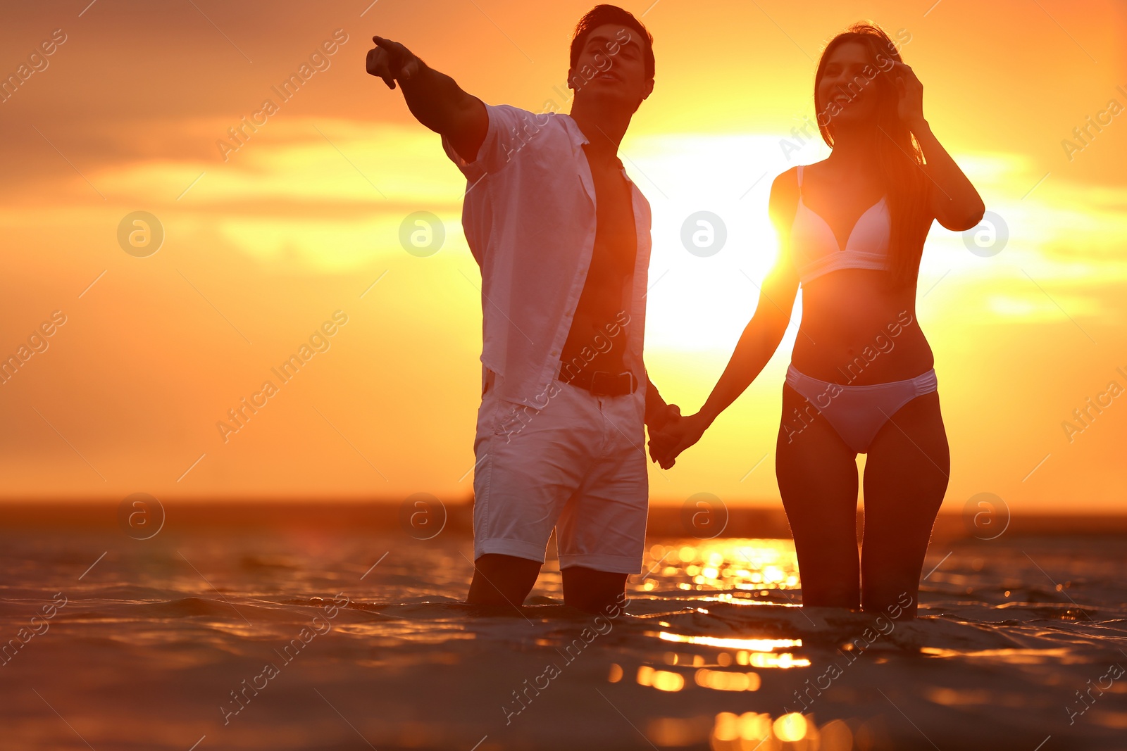 Photo of Happy young couple spending time together on sea beach at sunset