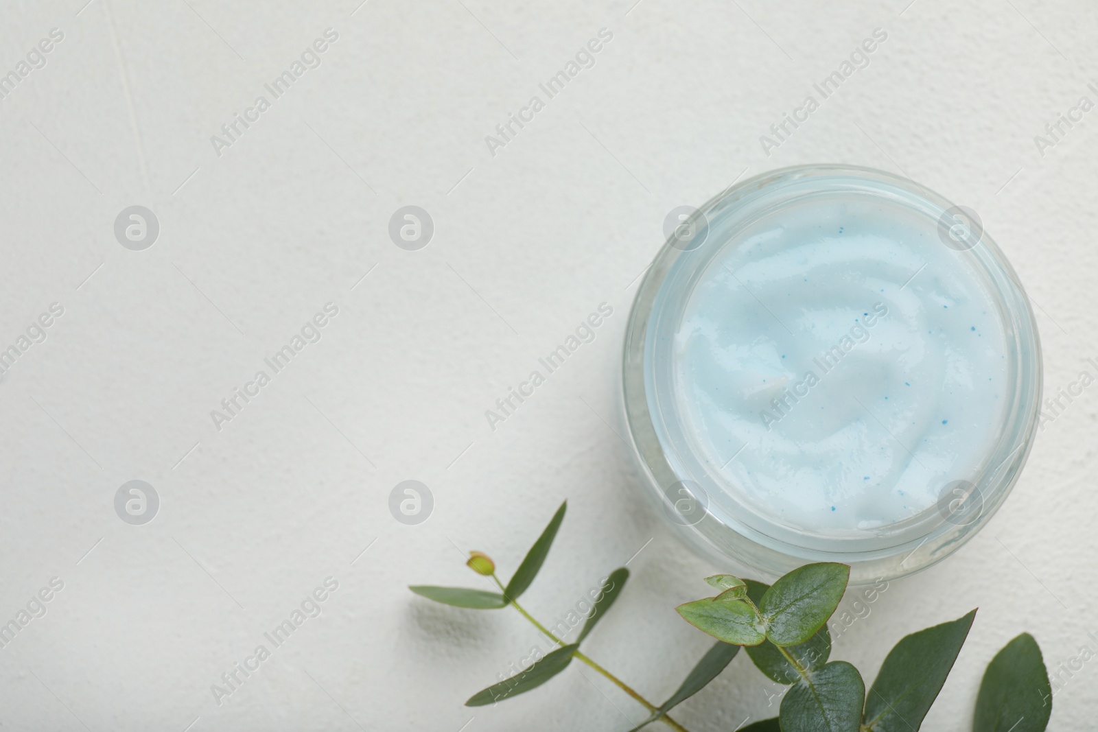 Photo of Jar of organic cream and eucalyptus on white table, flat lay. Space for text
