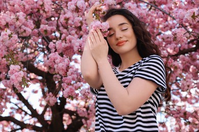 Beautiful woman near blossoming sakura tree on spring day