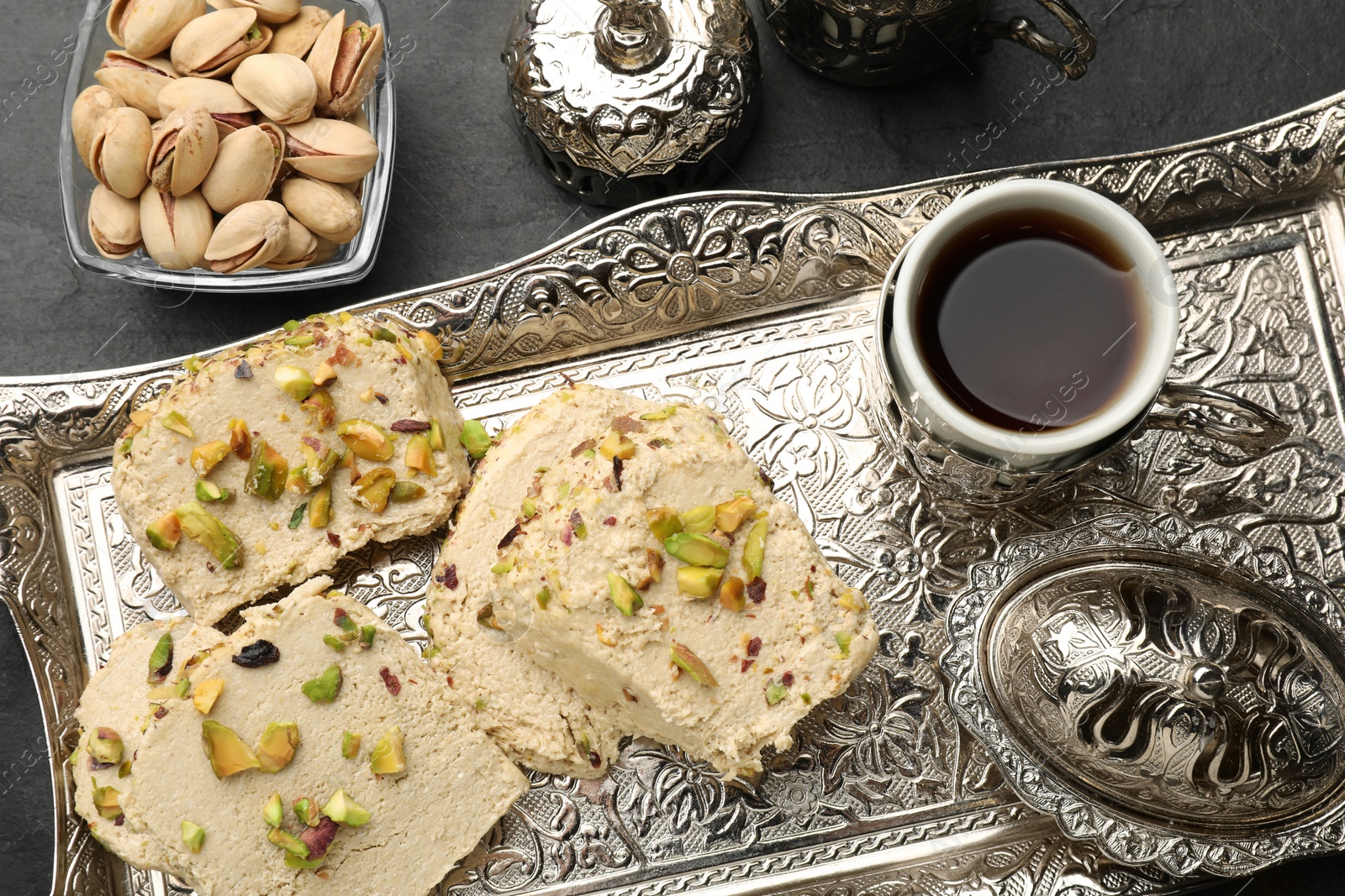 Photo of Tasty halva with pistachios served on grey table, flat lay