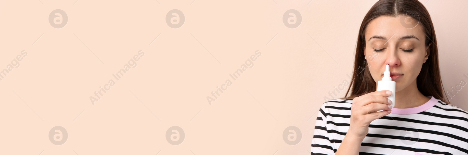 Photo of Woman using nasal spray on beige background. Space for text