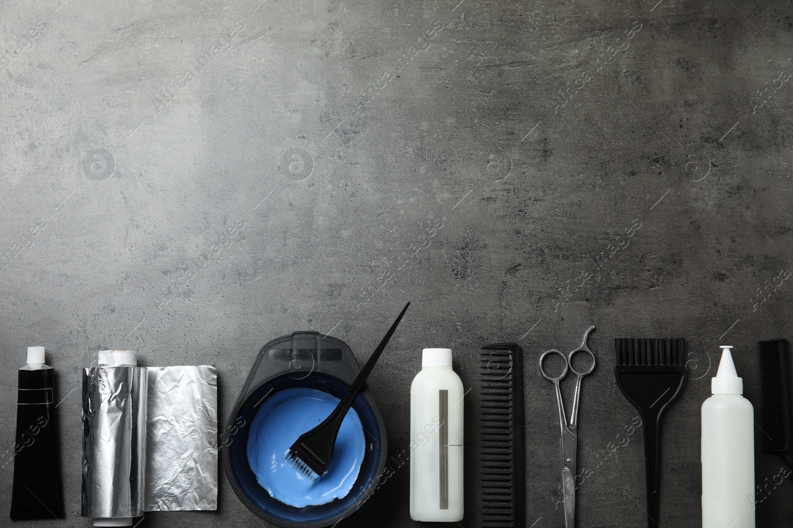 Photo of Professional tools for hair dyeing on grey stone background, flat lay. Space for text