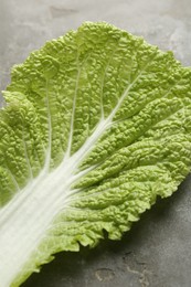 Fresh Chinese cabbage leaf on gray textured table, closeup