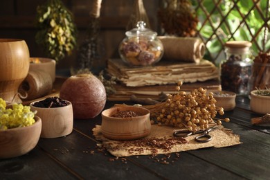 Photo of Different dry flowers, flax seeds and scissors on black wooden table indoors