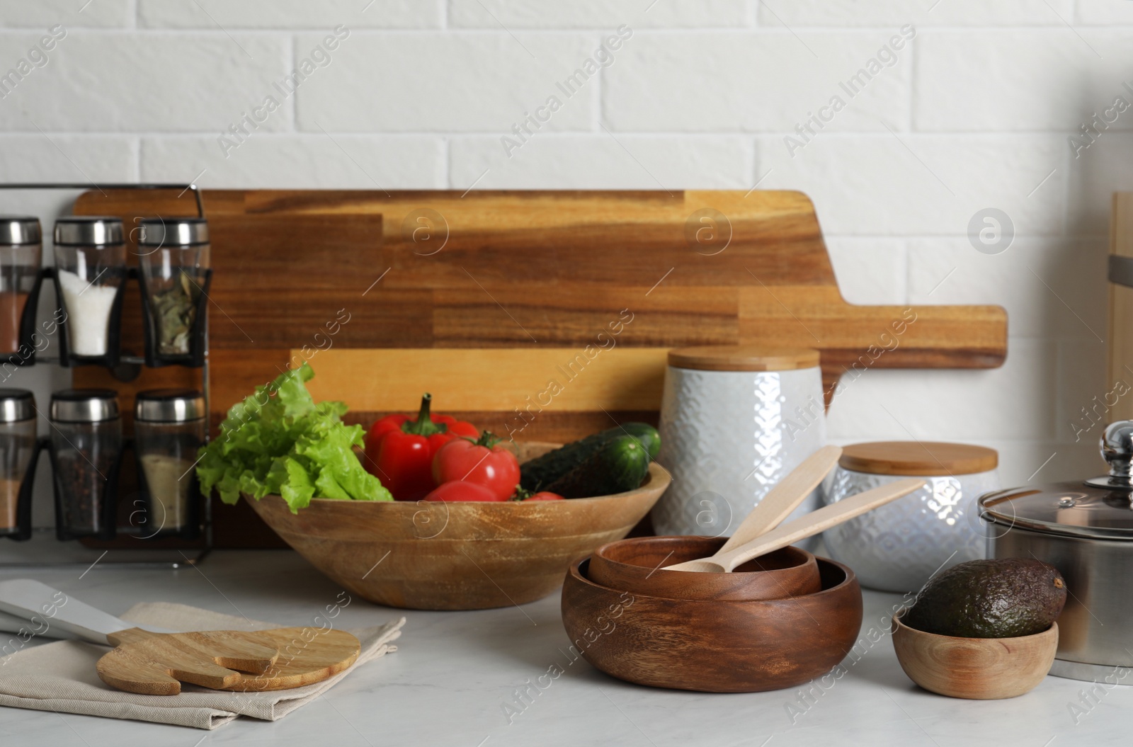 Photo of Different cooking utensils and fresh vegetables on countertop in kitchen