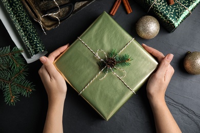 Photo of Woman with gift box at black table, top view