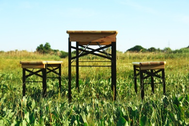 Photo of Wooden picnic table with benches in field on sunny day