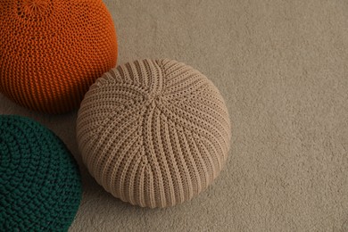 Different stylish knitted poufs on carpet indoors, space for text