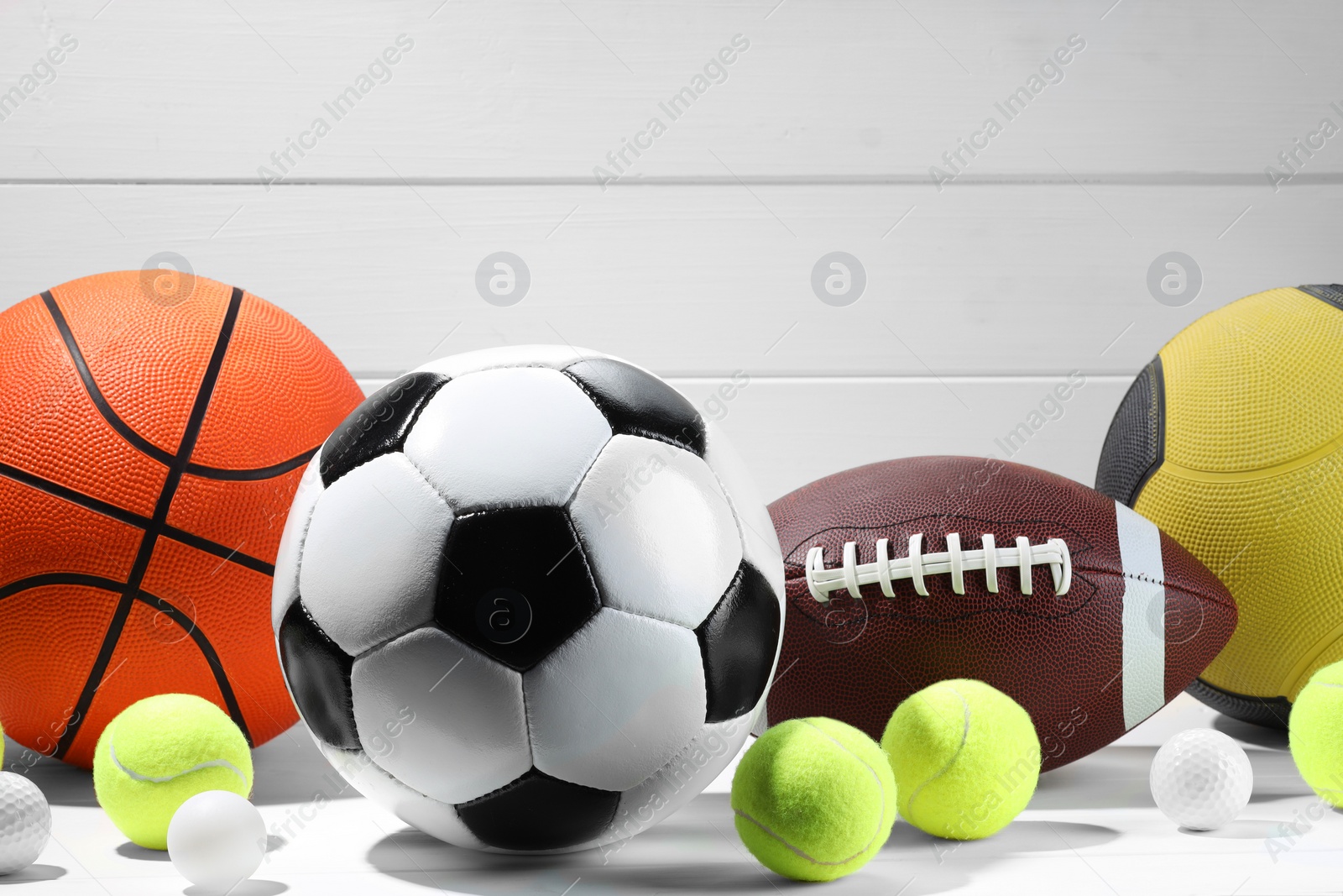 Photo of Many different sport balls on white wooden background