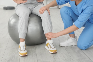 Photo of Professional physiotherapist working with female patient in rehabilitation center, closeup