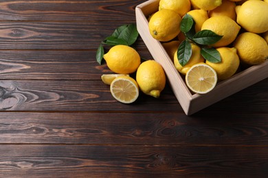 Fresh lemons in crate on wooden table. Space for text