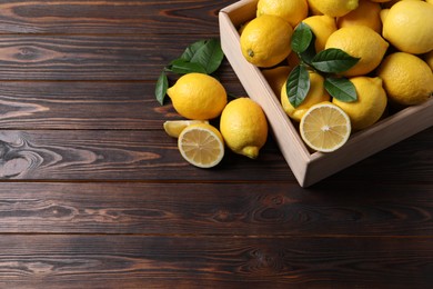 Photo of Fresh lemons in crate on wooden table. Space for text