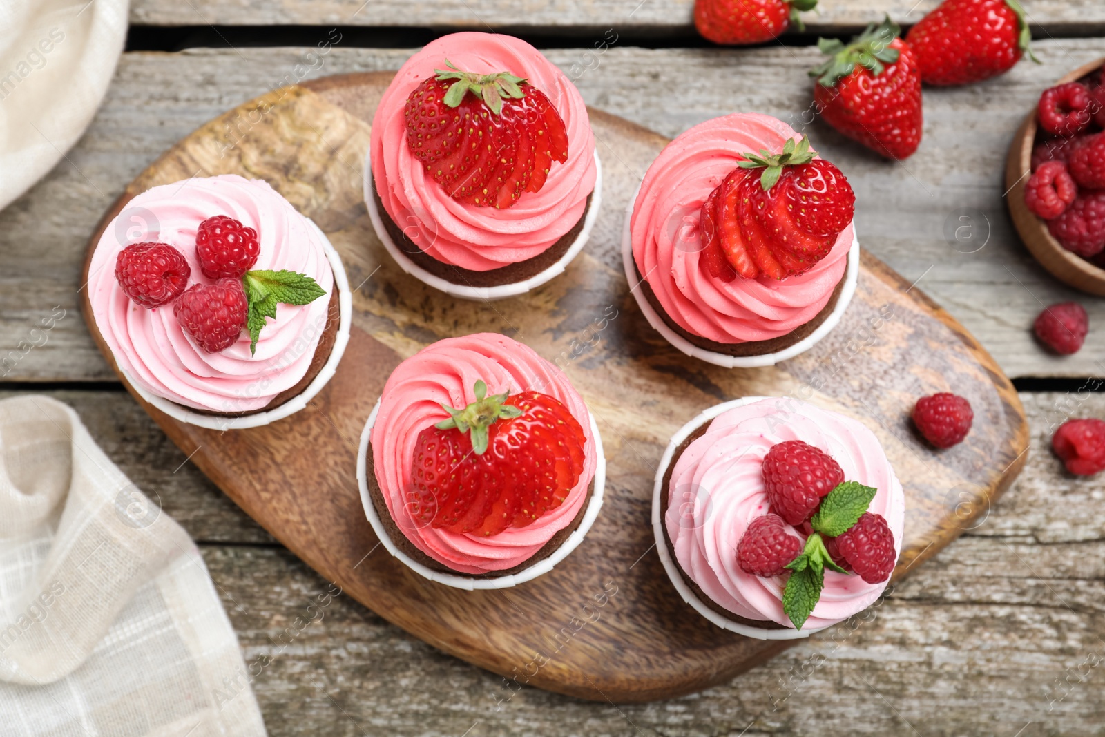 Photo of Sweet cupcakes with fresh berries on wooden table, flat lay