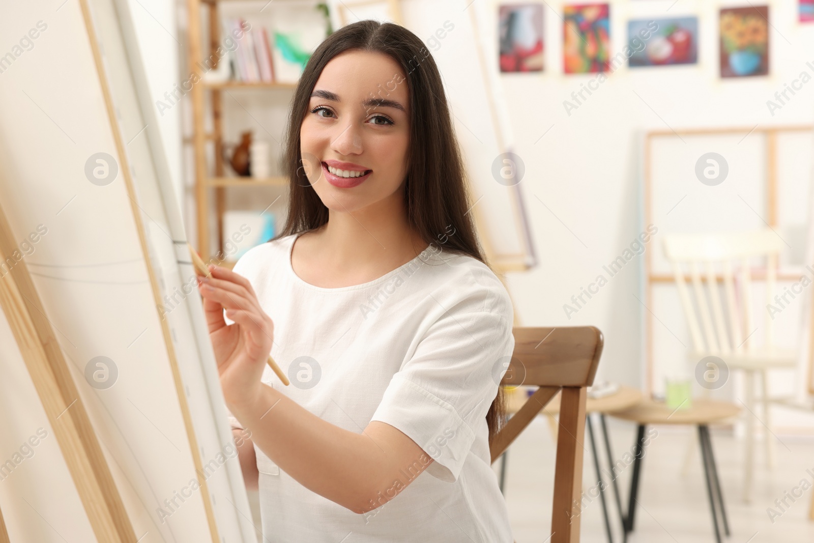 Photo of Beautiful young woman painting with brush in studio. Creative hobby