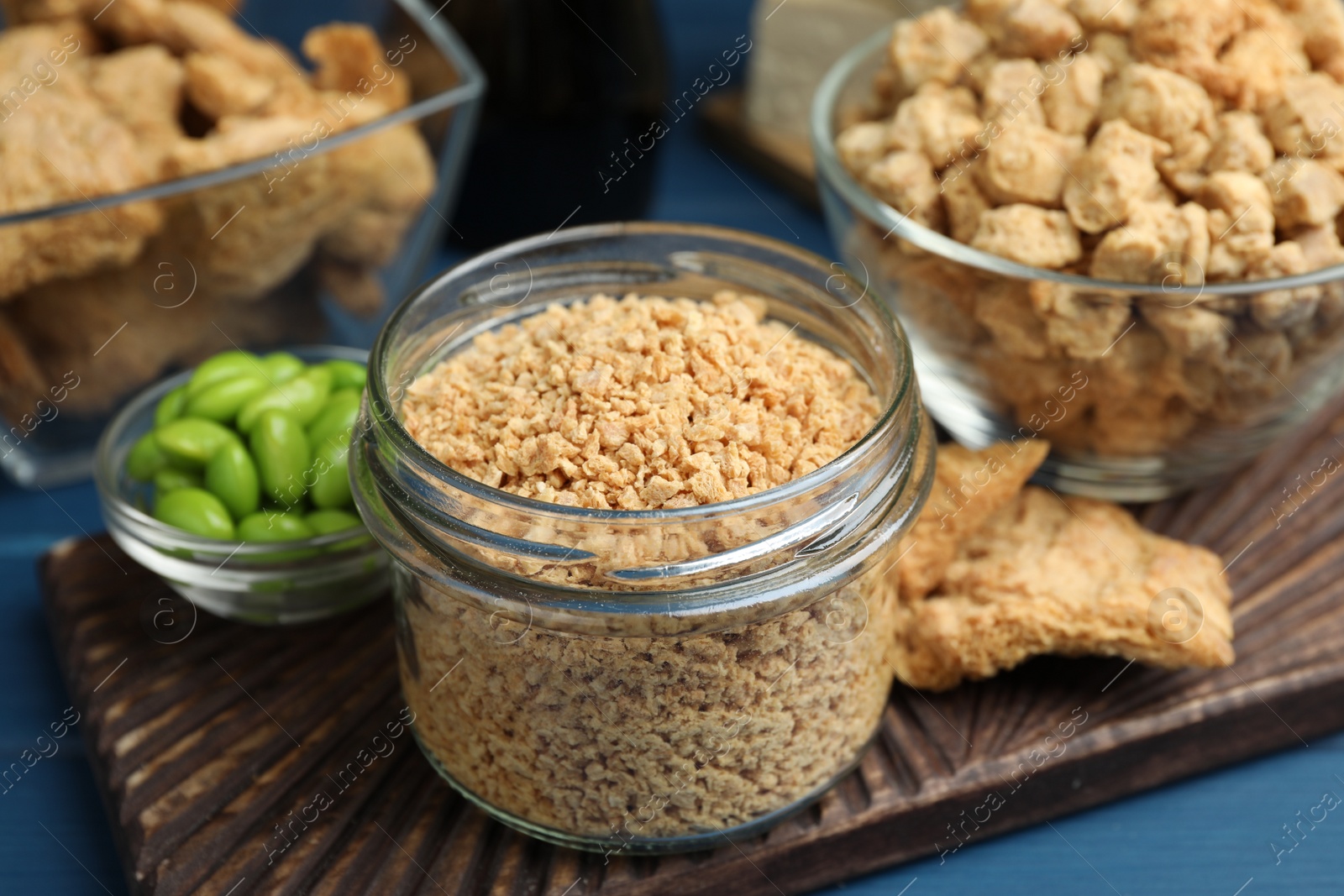 Photo of Dehydrated soy meat and other organic products on blue table, closeup