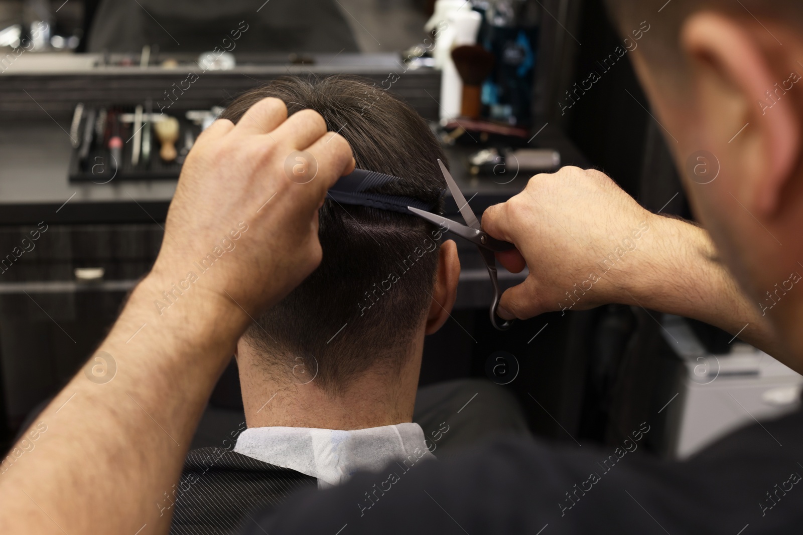 Photo of Professional hairdresser cutting man's hair in barbershop