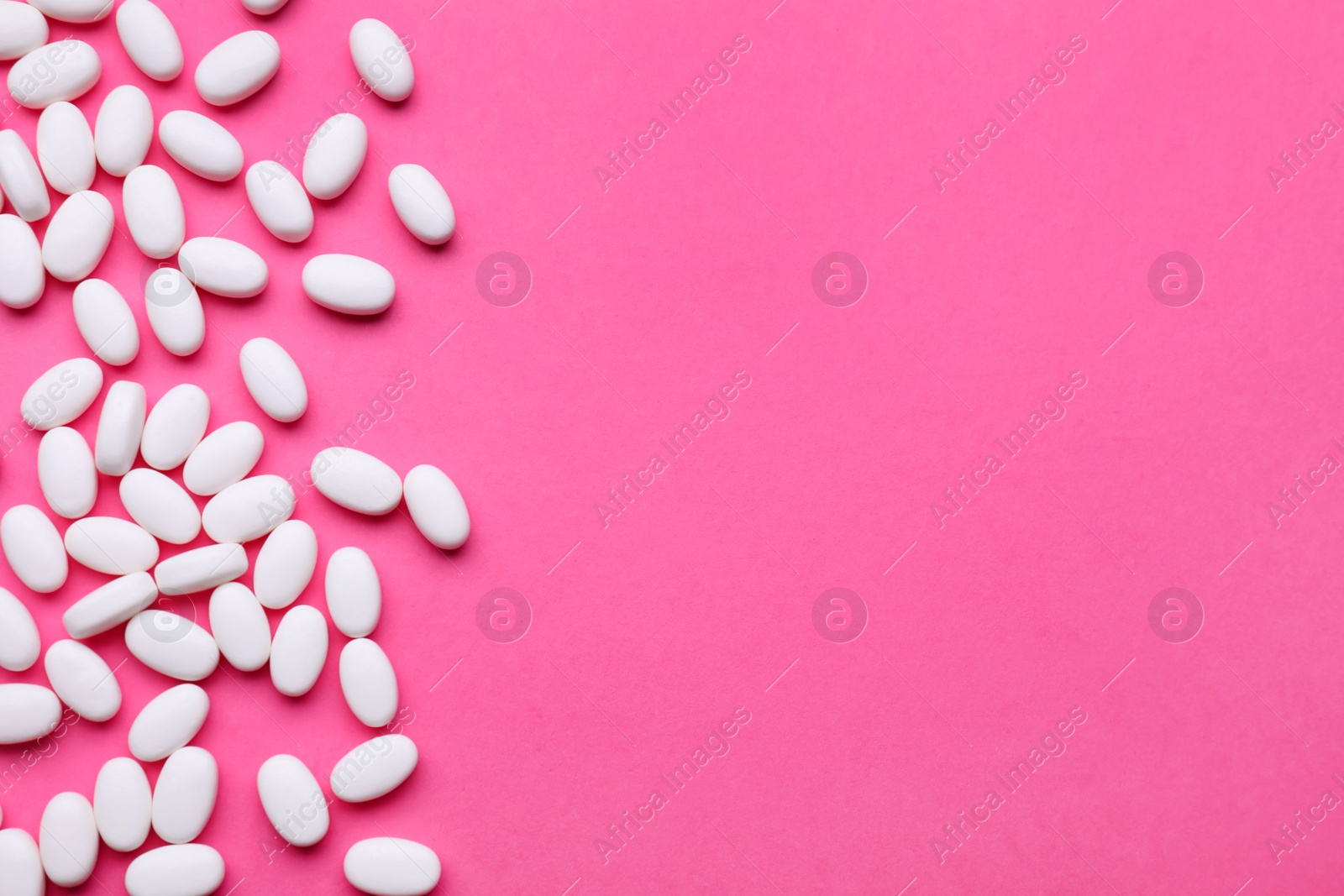 Photo of Many dragee candies on pink background, flat lay. Space for text