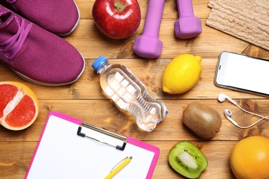 Photo of Flat lay composition with sport items, healthy food and clipboard on wooden background. Weight loss concept