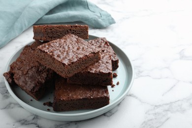 Photo of Delicious chocolate brownies on white marble table. Space for text