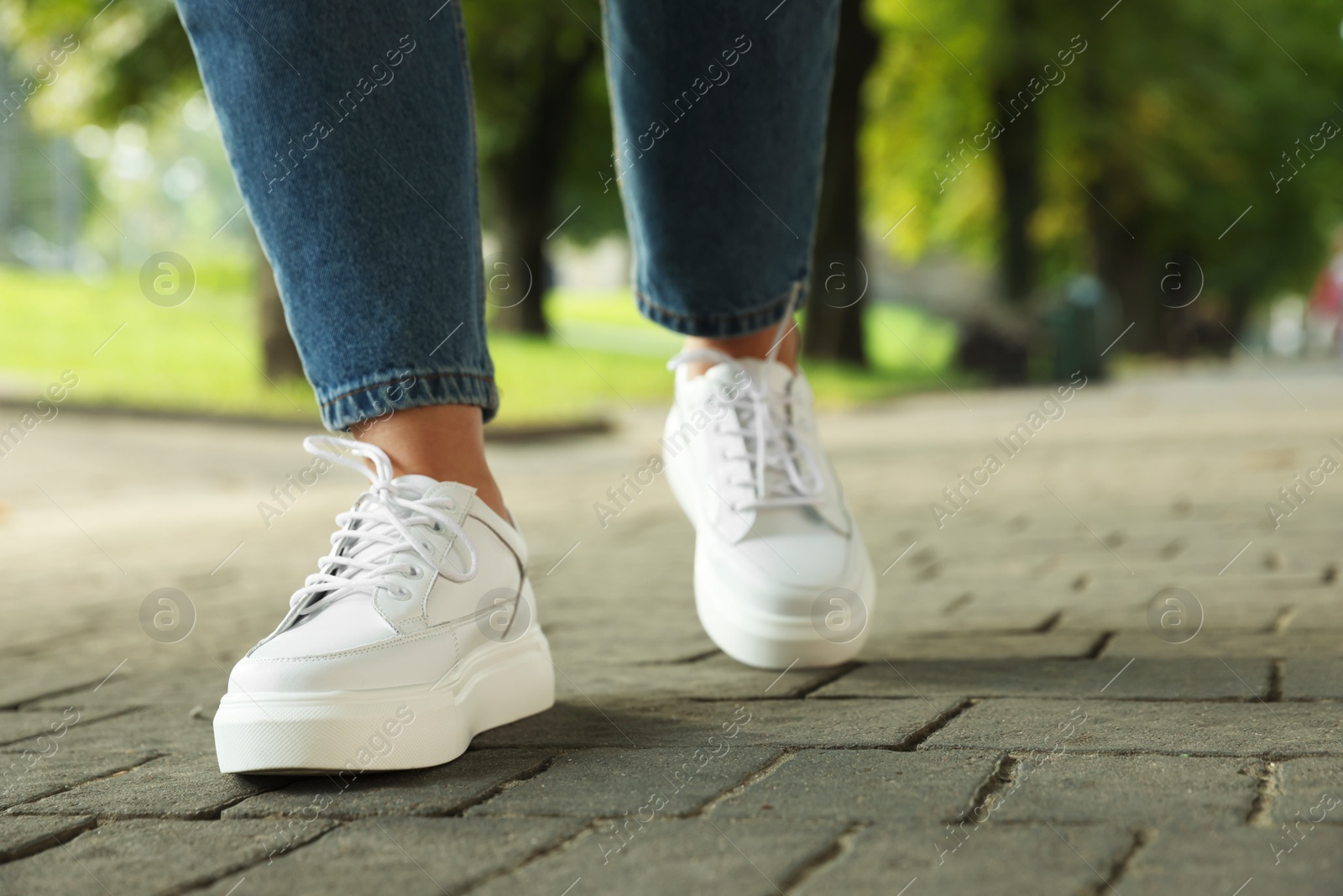 Photo of Woman in stylish sneakers walking on city street, closeup