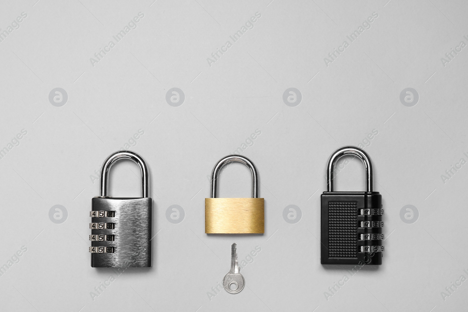 Photo of Different padlocks and key on grey background, flat lay. Space for text