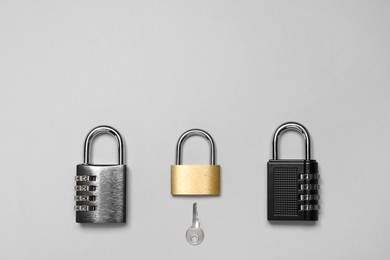 Photo of Different padlocks and key on grey background, flat lay. Space for text