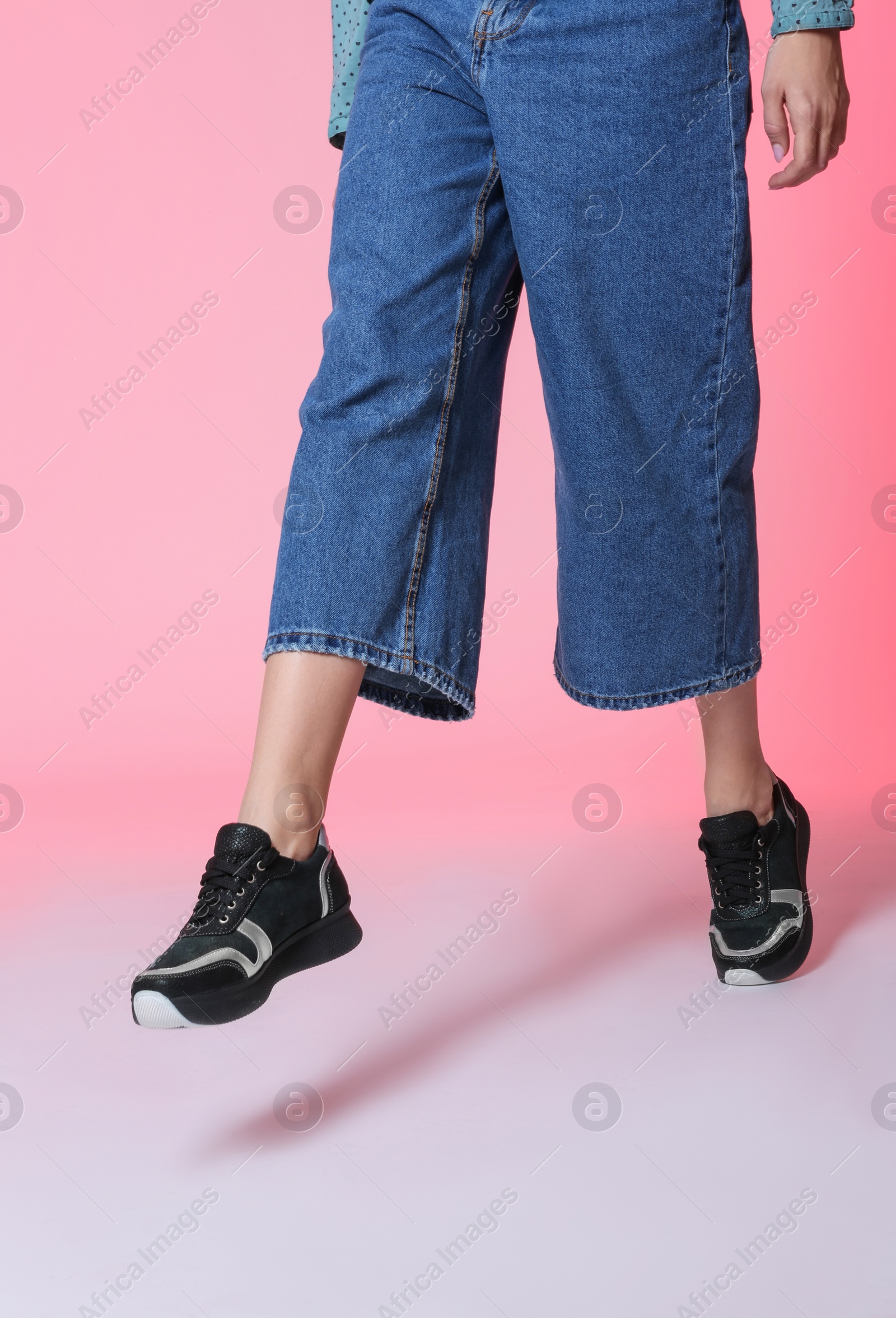 Photo of Woman in stylish shoes walking on color background, closeup