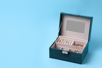 Jewelry box with many different accessories on light blue background, space for text