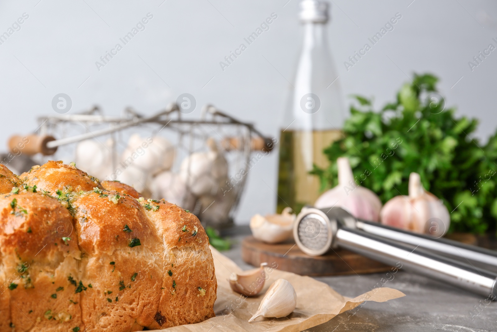 Photo of Buns of bread with garlic and herbs on grey table against light background