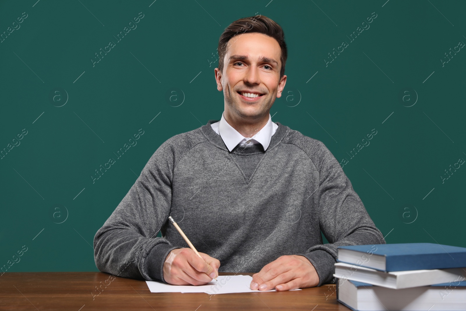 Photo of Portrait of male teacher working at table against color background