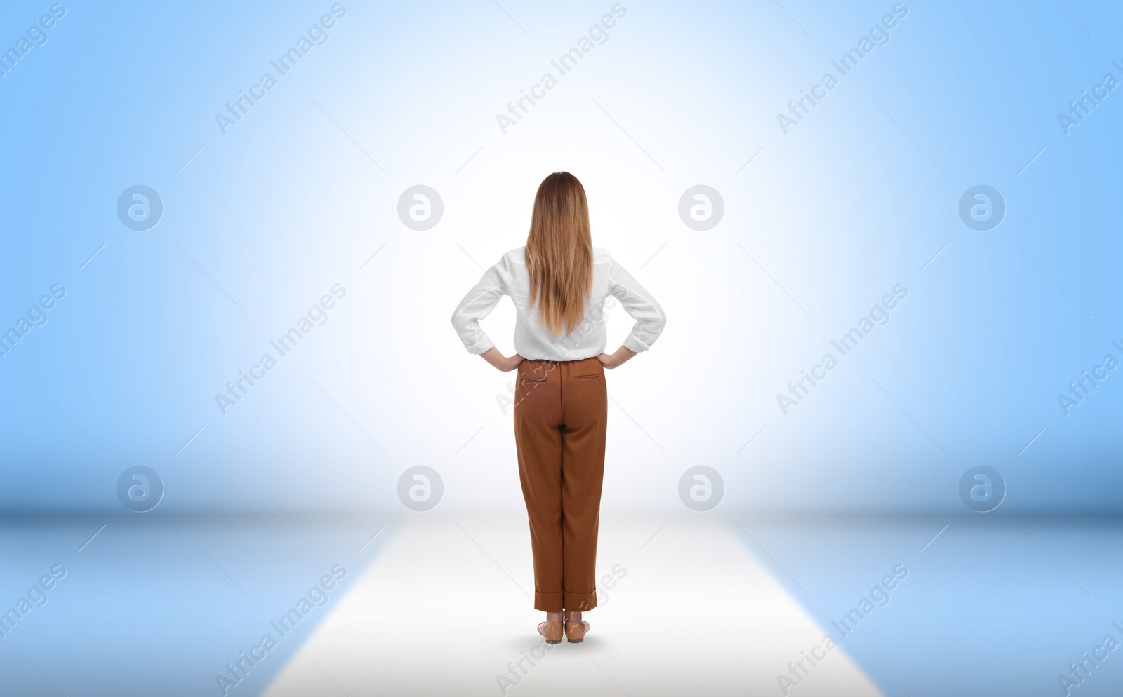 Image of Woman standing in front of light blue wall, back view