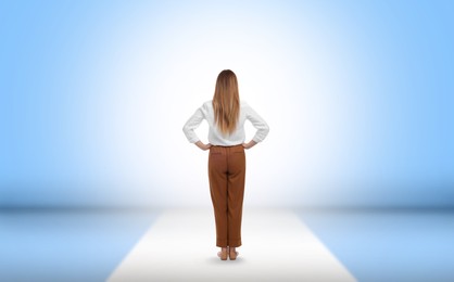 Woman standing in front of light blue wall, back view