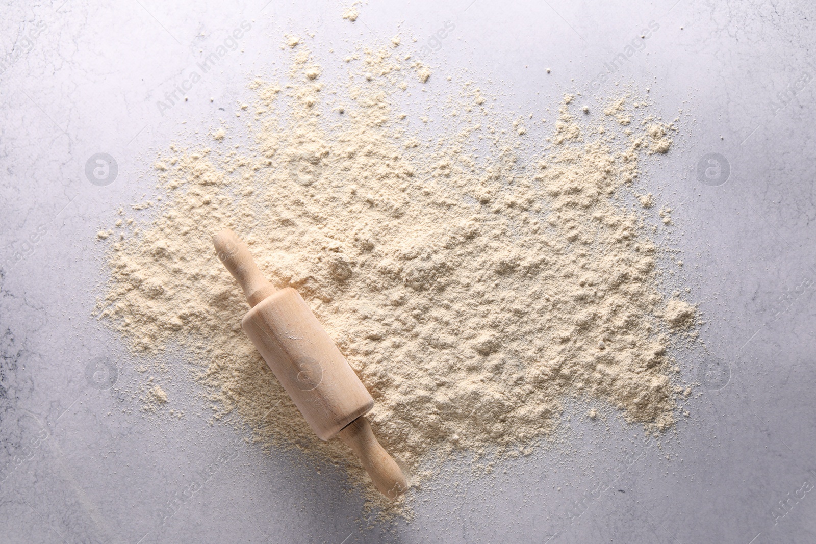 Photo of Pile of flour and rolling pin on light textured table, top view