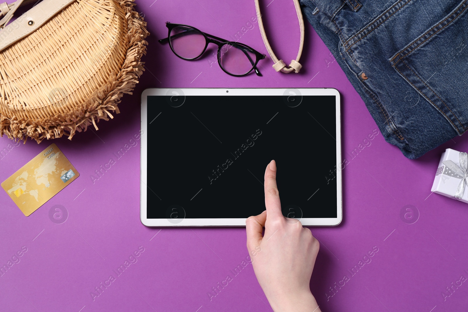 Photo of Online store. Woman using tablet on purple background, top view