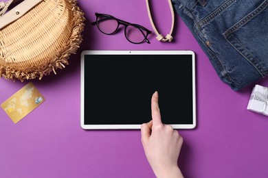 Online store. Woman using tablet on purple background, top view