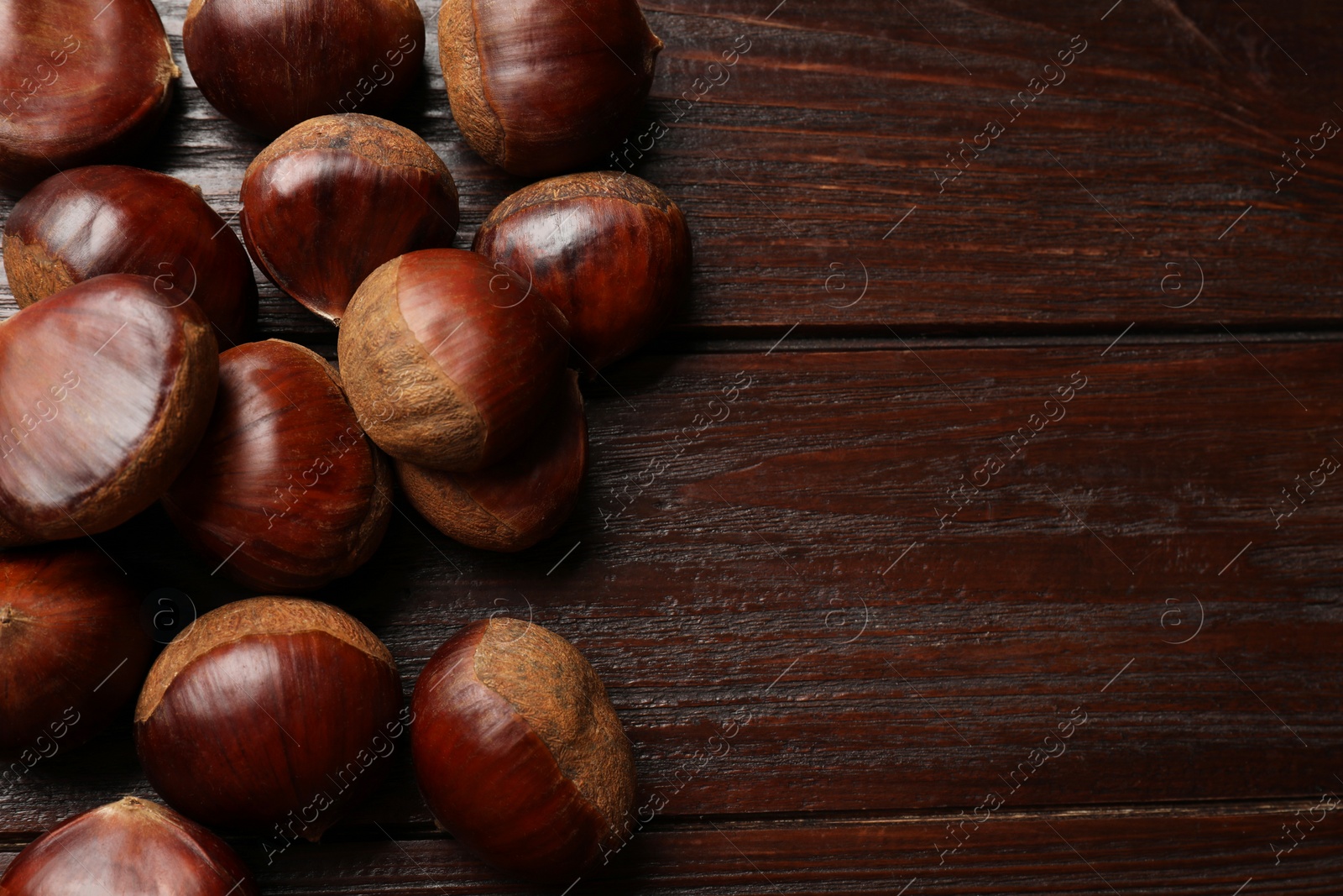 Photo of Sweet fresh edible chestnuts on wooden table, top view. Space for text