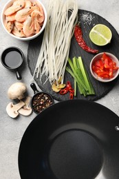 Photo of Flat lay composition with black wok, spices and products on grey textured table