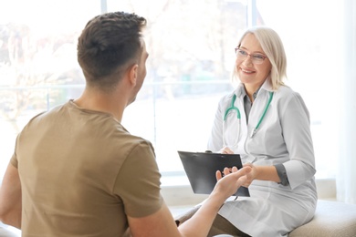 Photo of Mature doctor consulting patient at home