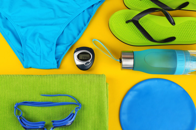 Flat lay composition with swimming accessories on yellow background