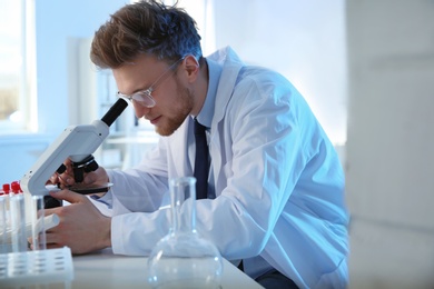 Photo of Male scientist using modern microscope in chemistry laboratory