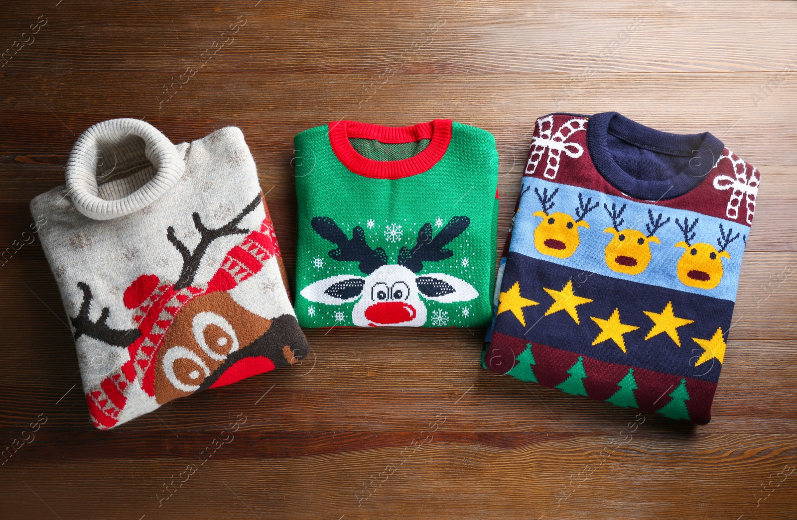 Photo of Folded warm Christmas sweaters on wooden table, flat lay