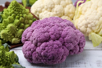 Photo of Different fresh cabbages on white wooden table, closeup